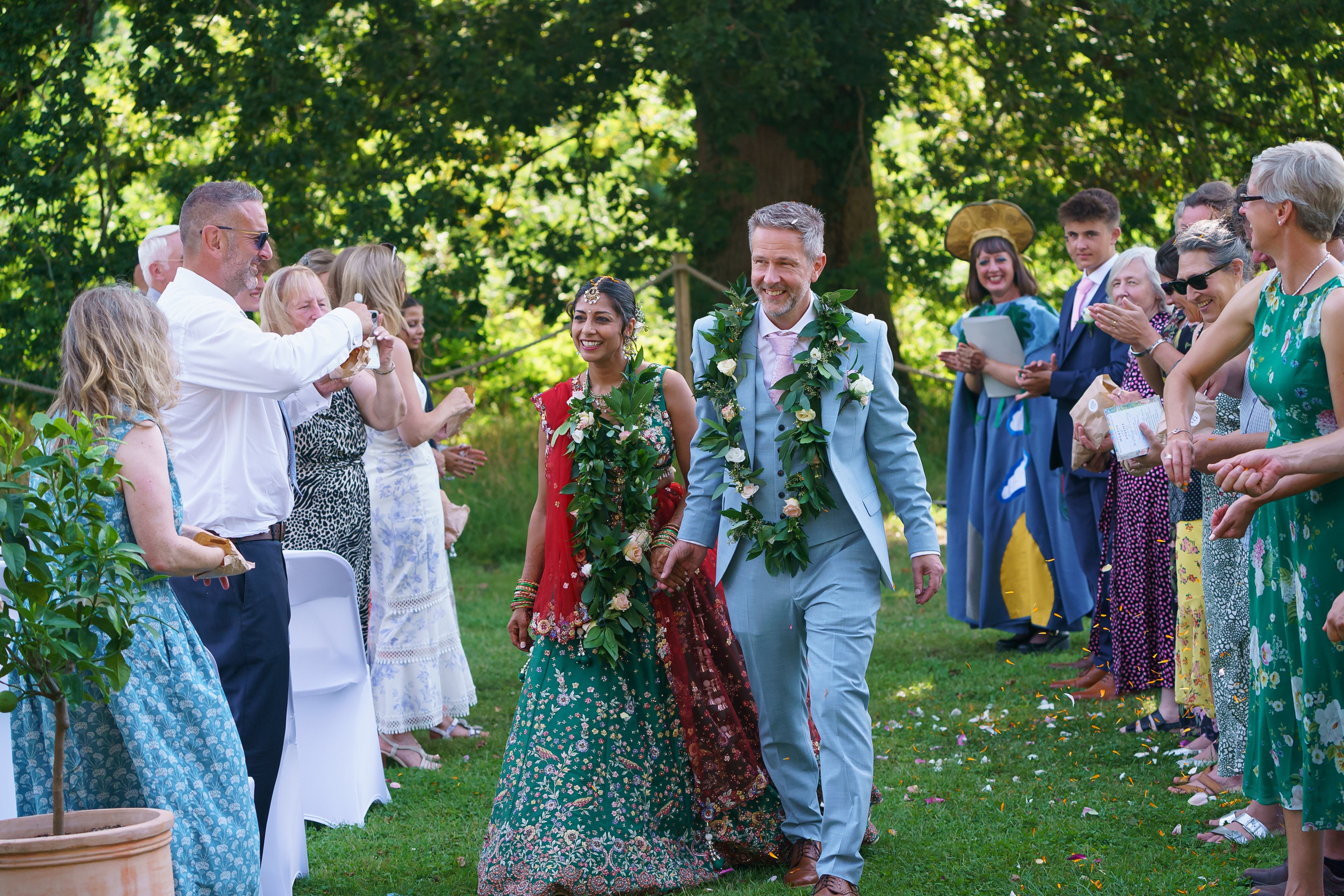 Wedding ceremony at Carey’s under the oak tree, with guests joyfully throwing flower petal confetti, celebrating a beautiful, sustainable wedding in nature.