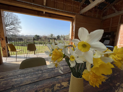 Daffodils in a vase in the Reclaimed Barn at Carey’s, showcasing the rustic charm of the space, available for hire for events, gatherings, and special occasions in a beautiful setting