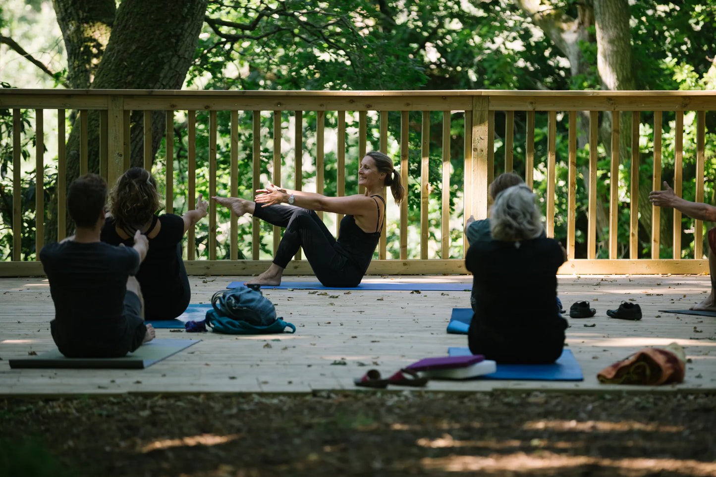 Women’s yoga class at Carey’s, with participants practicing poses outdoors on a wooden platform in a woodland setting, surrounded by nature and peaceful ambiance