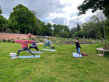 Women’s yoga class at Carey’s, with participants practicing poses outdoors in a serene garden setting, surrounded by nature and the peaceful ambiance of the garden.